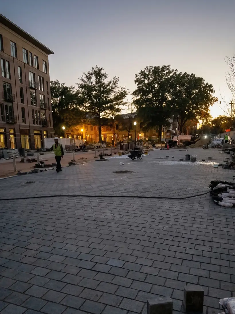 Plaza al crepúsculo con luces de cuerda y árboles jóvenes